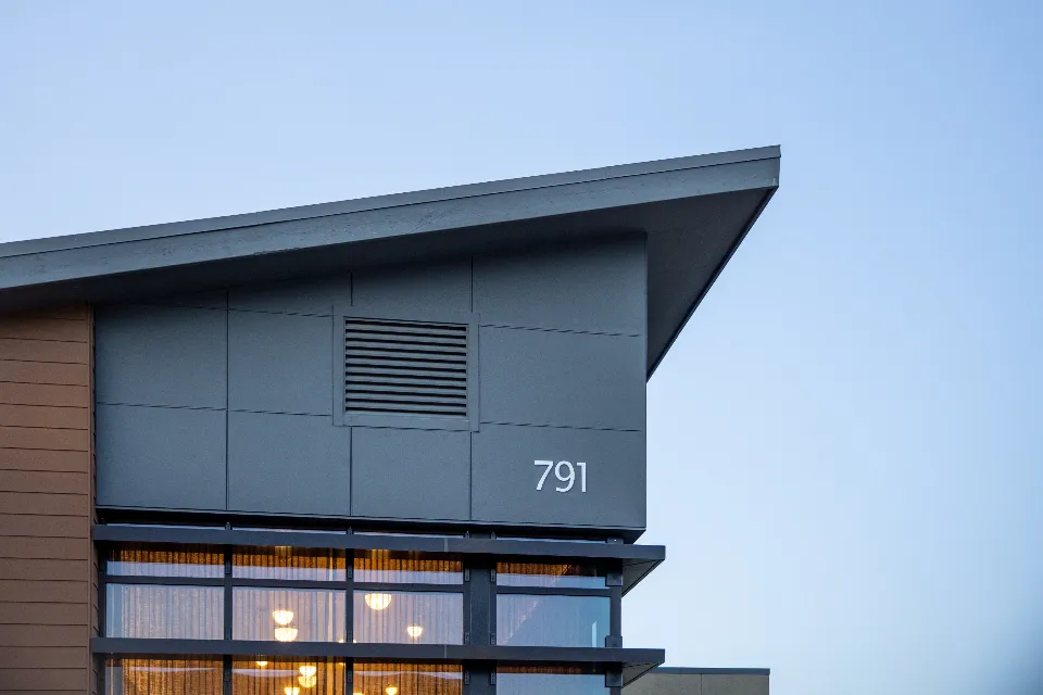 A modern building with a projecting canopy and a number plate on the wall.